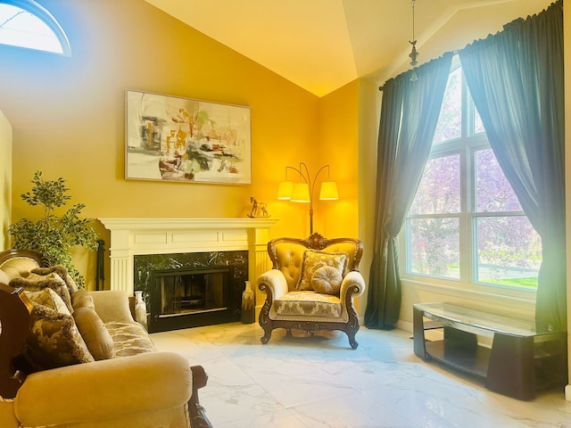 living area featuring vaulted ceiling, a fireplace, and marble finish floor