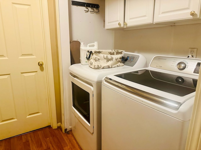 clothes washing area with dark wood-type flooring, washer and clothes dryer, and cabinet space