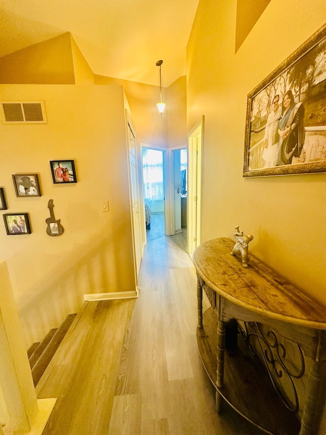hallway featuring wood finished floors, visible vents, and stairs