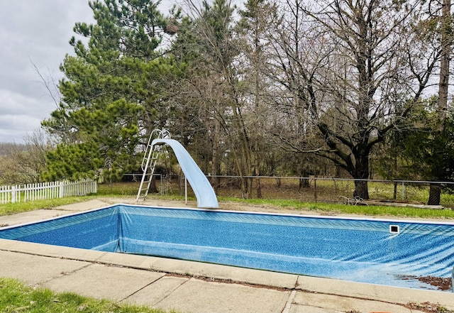 view of swimming pool featuring fence, a fenced in pool, and a water slide