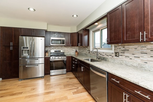 kitchen with light stone counters, stainless steel appliances, decorative backsplash, and a sink