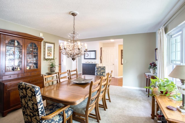 dining area with baseboards, light carpet, a textured ceiling, and an inviting chandelier