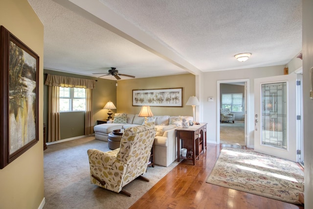 living area with a textured ceiling, a ceiling fan, and baseboards