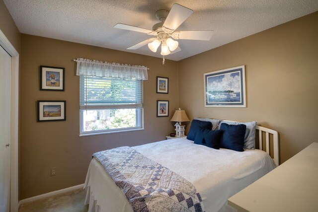 bedroom with a textured ceiling, carpet flooring, baseboards, and ceiling fan
