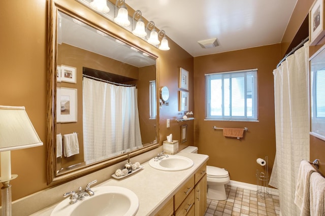 bathroom featuring visible vents, a sink, double vanity, and toilet