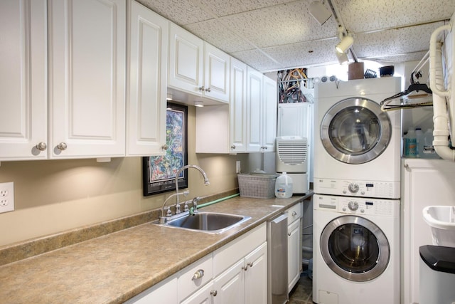 laundry area featuring cabinet space, stacked washing maching and dryer, and a sink