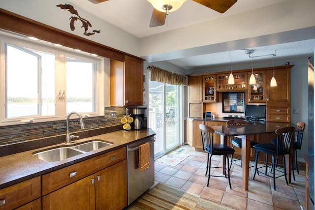 kitchen featuring brown cabinets, dark countertops, dishwasher, and a sink