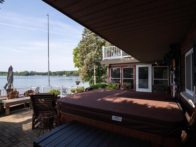 wooden terrace with a water view, a covered hot tub, and a patio