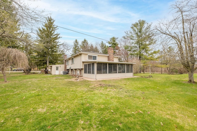 back of house featuring a lawn, a chimney, and a sunroom