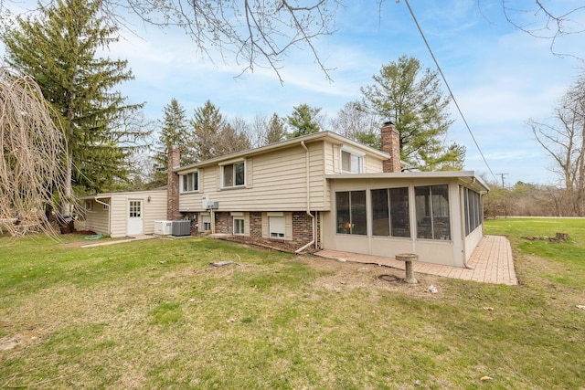 back of property with a chimney, a sunroom, a yard, and central AC
