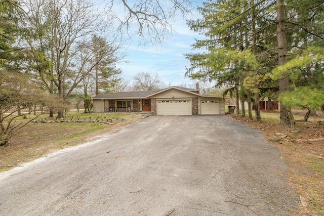ranch-style home featuring a garage, a porch, and aphalt driveway