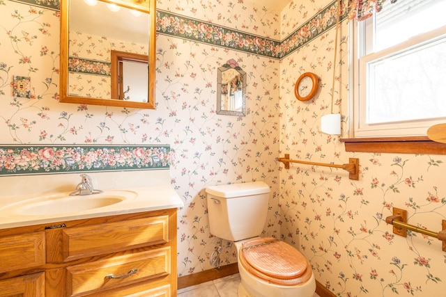 half bathroom with toilet, vanity, tile patterned floors, and wallpapered walls