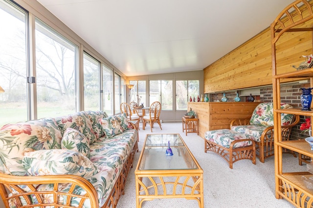 sunroom / solarium with vaulted ceiling, wooden walls, and carpet