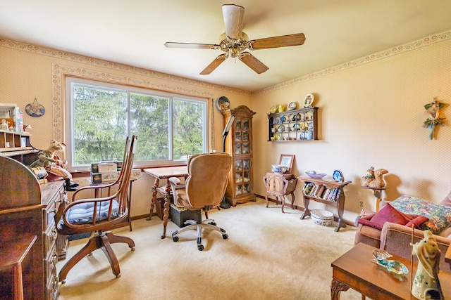 carpeted office with wallpapered walls and a ceiling fan