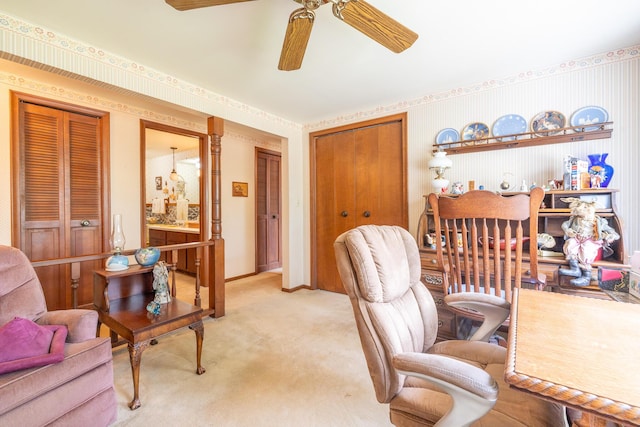 home office with wallpapered walls, a ceiling fan, baseboards, and light colored carpet