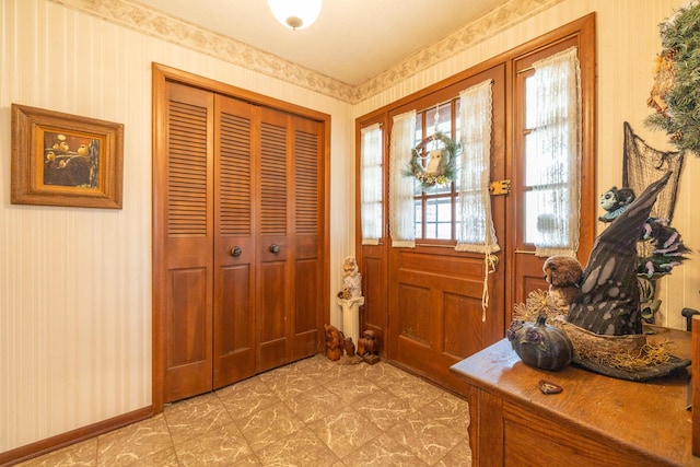 entryway with baseboards and wallpapered walls