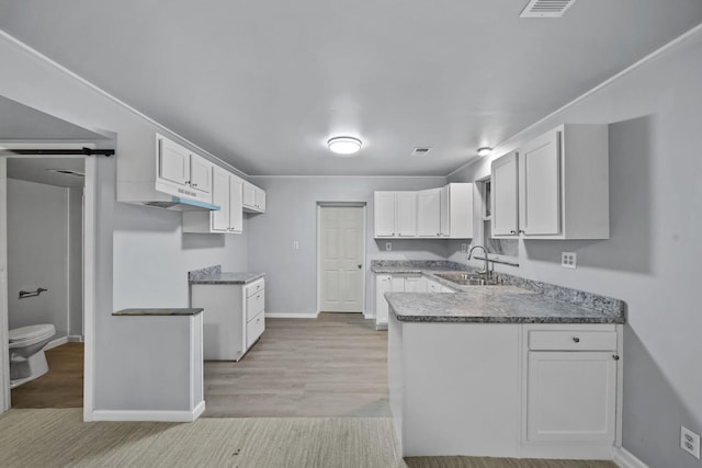 8825 Mills Rd, Manitou Beach, MI 49253 - kitchen with a sink, a peninsula, baseboards, white cabinets, and light wood finished floors