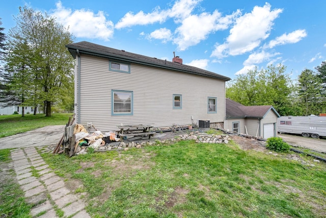 8825 Mills Rd, Manitou Beach, MI 49253 - rear view of property featuring a chimney, central AC unit, a lawn, and asphalt driveway