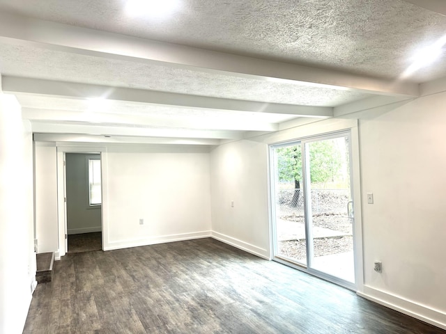 empty room featuring beamed ceiling, a wealth of natural light, and dark wood-style floors