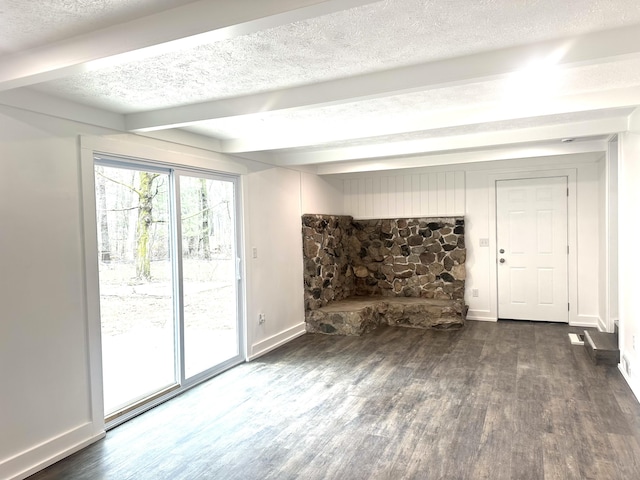 unfurnished living room with baseboards, beam ceiling, and wood finished floors