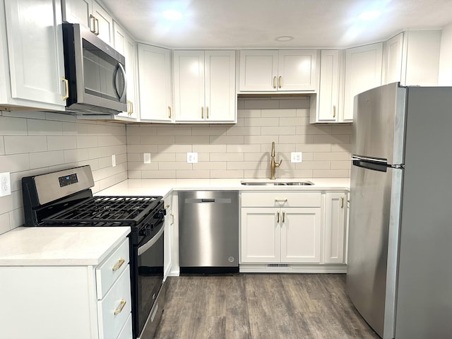 kitchen with dark wood-style floors, a sink, decorative backsplash, light countertops, and appliances with stainless steel finishes