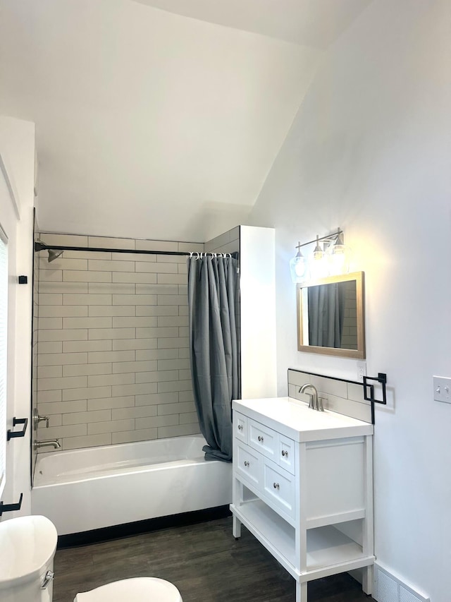 bathroom with wood finished floors, vanity, shower / bathtub combination with curtain, toilet, and lofted ceiling