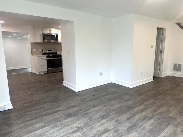 unfurnished living room featuring visible vents, baseboards, and dark wood-style floors