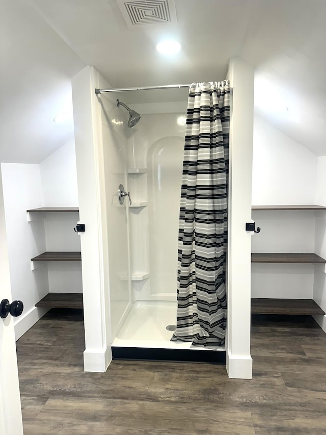 bathroom featuring wood finished floors, visible vents, a shower stall, and vaulted ceiling