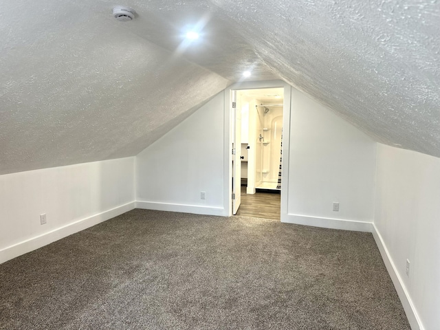 bonus room featuring lofted ceiling, carpet flooring, a textured ceiling, and baseboards