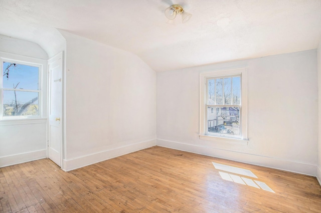 empty room featuring vaulted ceiling, light wood-style floors, and plenty of natural light