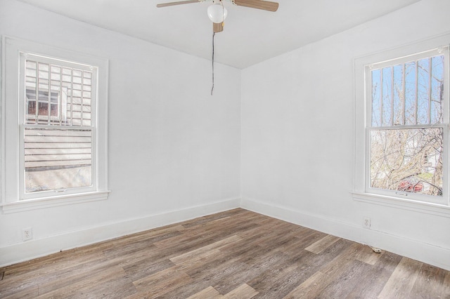spare room with baseboards, a ceiling fan, wood finished floors, and plenty of natural light