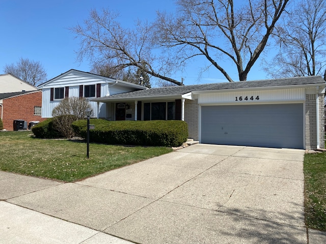 split level home featuring brick siding, a front lawn, driveway, and a garage