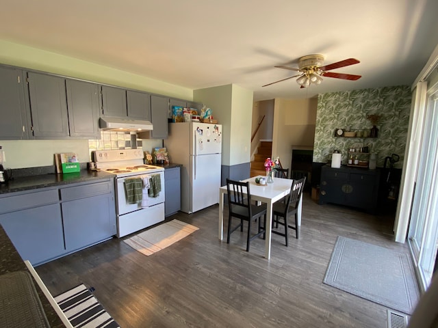 kitchen featuring under cabinet range hood, dark countertops, visible vents, a ceiling fan, and white appliances