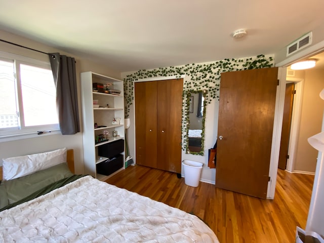 bedroom featuring wood finished floors and visible vents