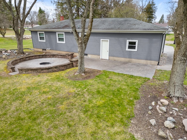 rear view of property with a chimney, a patio, a lawn, a fire pit, and roof with shingles