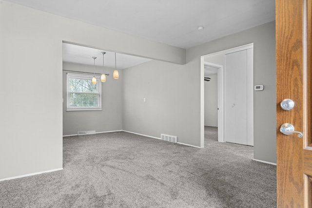 spare room with baseboards, carpet flooring, and visible vents