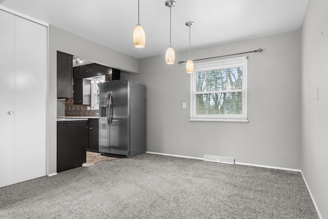 kitchen featuring visible vents, light colored carpet, pendant lighting, stainless steel fridge with ice dispenser, and dark cabinets