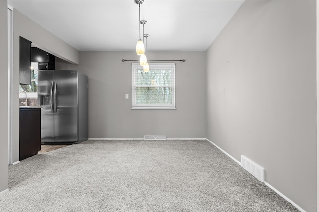 unfurnished dining area featuring visible vents, carpet flooring, baseboards, and a sink