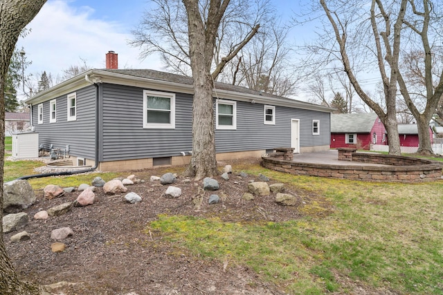 back of house with a yard, a patio, and a chimney