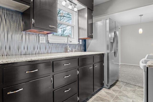 kitchen with decorative light fixtures, range, light stone counters, and light colored carpet