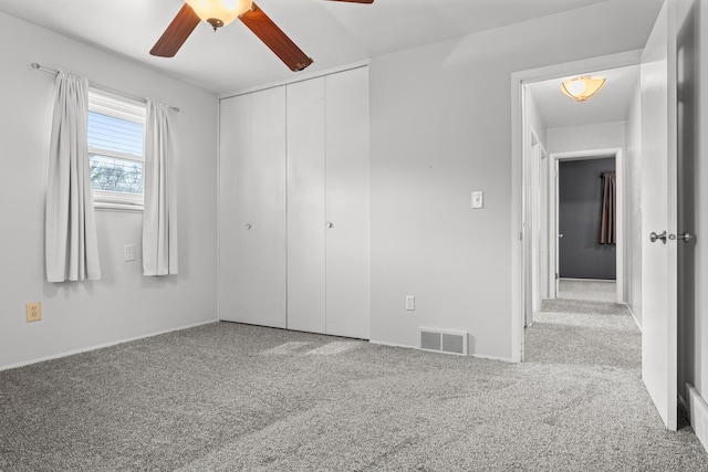 unfurnished bedroom featuring visible vents, carpet floors, a closet, and ceiling fan