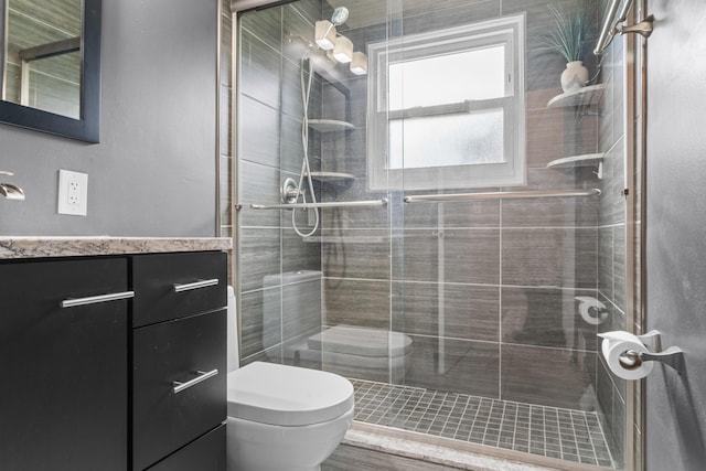 full bathroom featuring vanity, a shower stall, and toilet