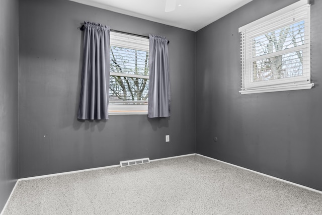 carpeted spare room featuring baseboards, a ceiling fan, and visible vents