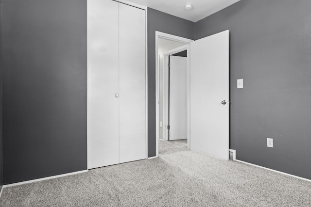 unfurnished bedroom with carpet, a closet, and baseboards