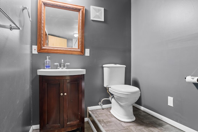 bathroom featuring visible vents, baseboards, vanity, and toilet