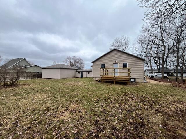 rear view of house featuring fence, a wooden deck, and a lawn