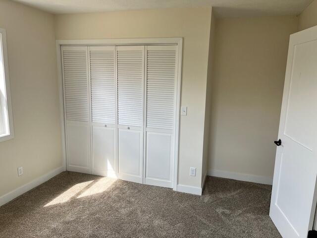 unfurnished bedroom with carpet floors, a closet, and baseboards