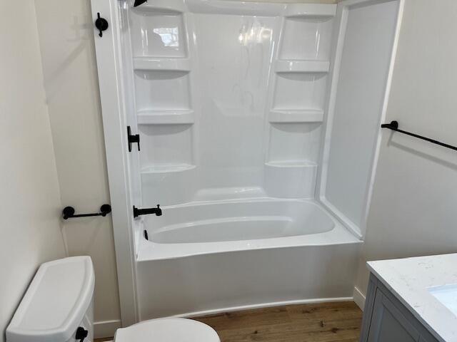 bathroom featuring toilet, vanity, wood finished floors, and  shower combination