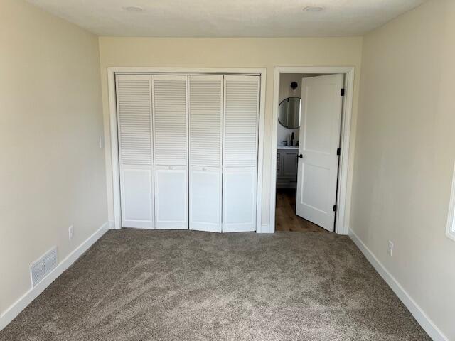 unfurnished bedroom featuring baseboards, visible vents, a closet, and carpet flooring