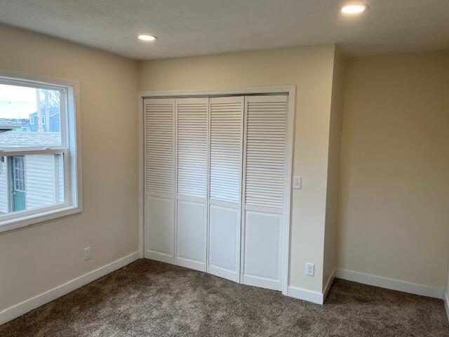 unfurnished bedroom with recessed lighting, baseboards, carpet floors, and a closet